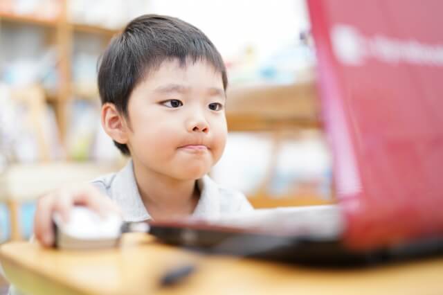 男の子が赤いパソコンを操作している画像