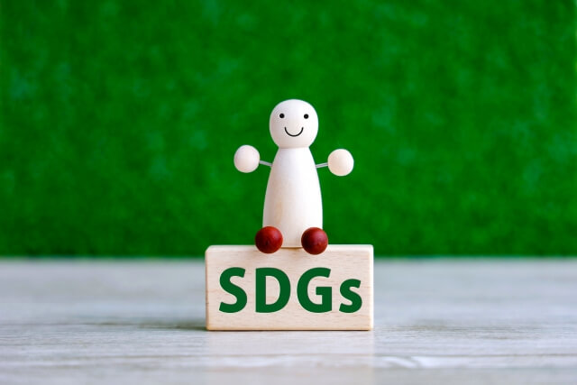 SDGsと書かれている木製のコマの上に人形が座っている画像