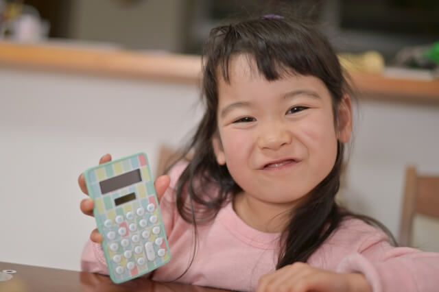 女の子が笑顔で電卓を持っている画像