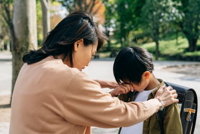 母親が泣いている男の子に話しかけている画像