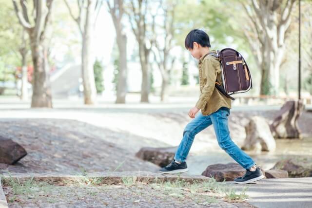 茶色のランドセルを背負った男のが道を歩いている画像