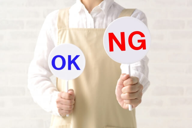 「OK」と「NG」と書いてある札を持った人が、「NG」札を前方に掲げている画像