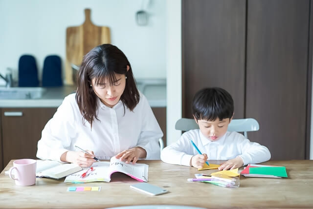 母親と子供が同じ机の上で勉強している画像