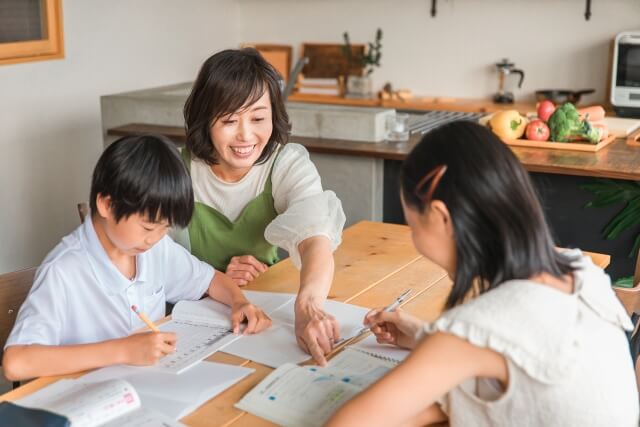 母親が二人の子供に勉強を教えている様子