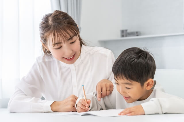 女性が男の子に勉強を教えている様子