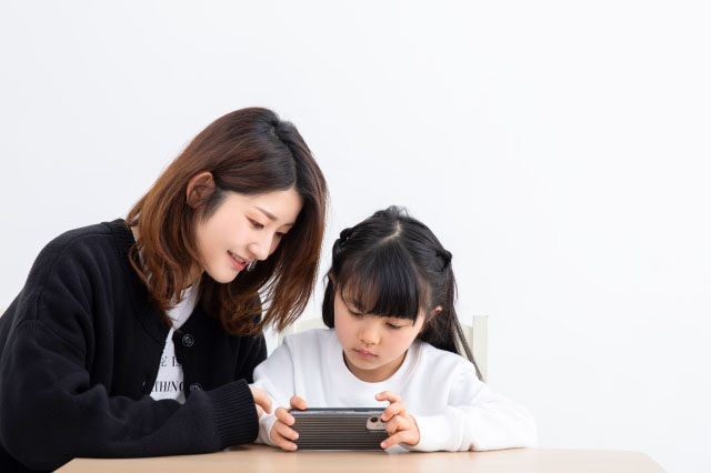 スマートフォン（スマホ）を見る親子の写真
