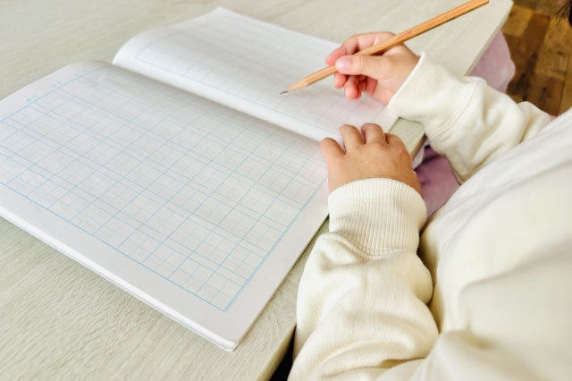ノートに何か書こうとしている子供の写真
