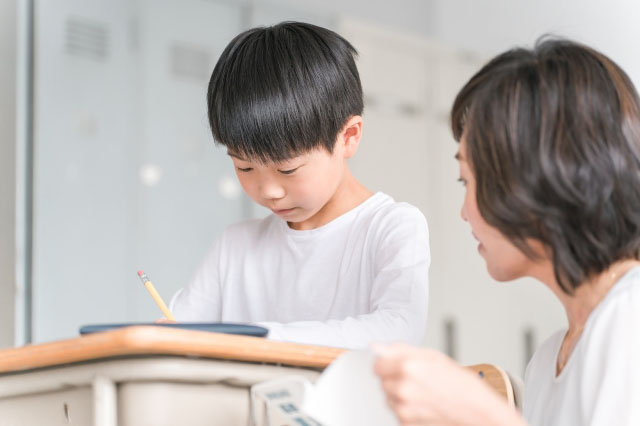 勉強する男の子を見る先生の写真