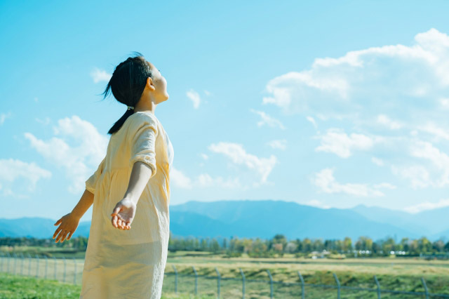 自然の中手を広げ風を感じる女の子の写真