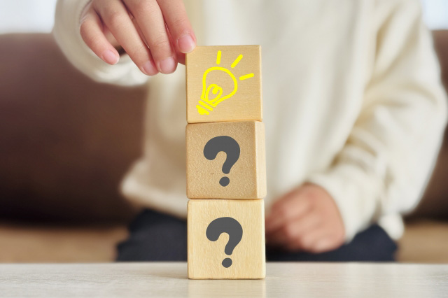 子供が積み木をしていて、積み木の下から一段目と二段目には「?」マーク、一番上の段には豆電球のマークが書かれている画像