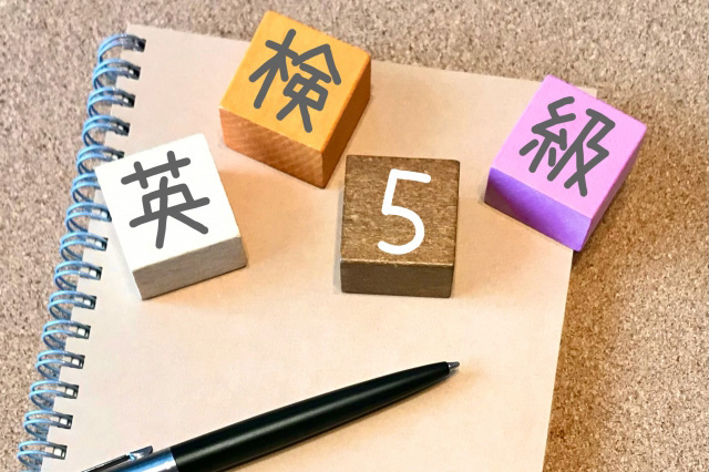 英検5級の文字が書かれた立方体４つとノートとペンの画像