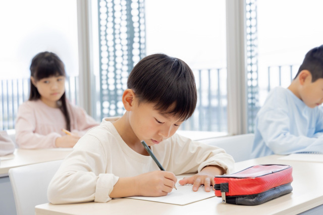 机に向かってノートをとる子供の画像
