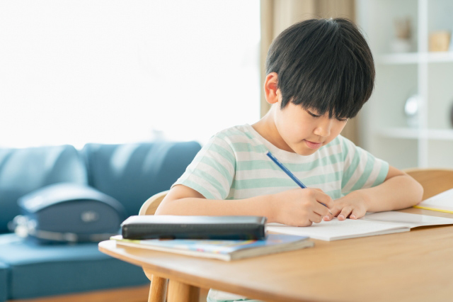家で机に向かって勉強する子供の画像