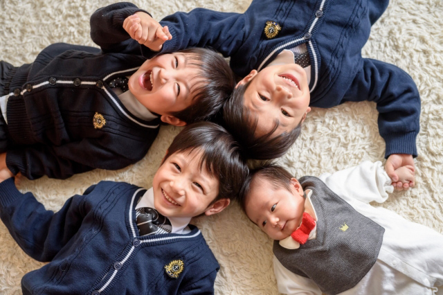 手をつないで輪になって寝転がっている子供たちの画像
