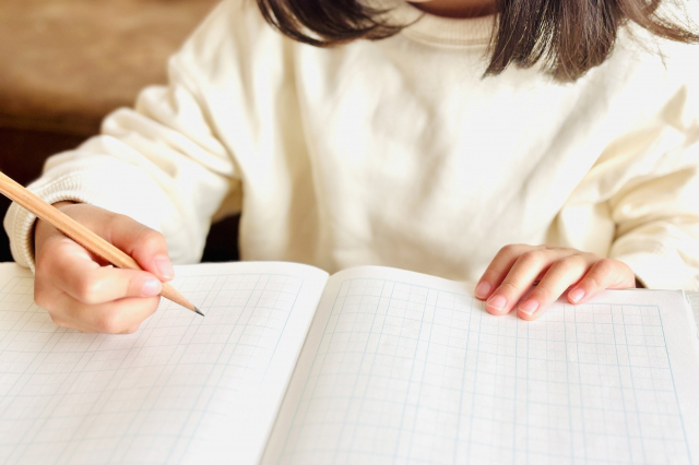漢字ノートを開き鉛筆を持っている子供の画像