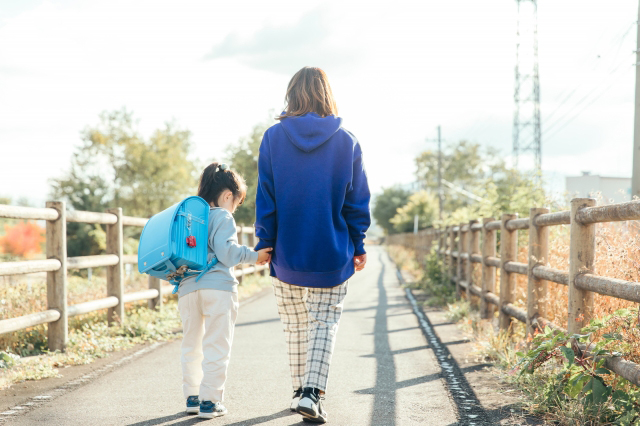 手をつなぎ歩いている親子の画像