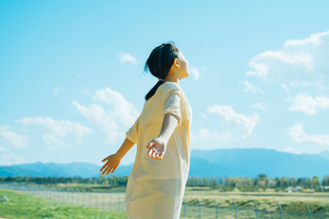 自然の中手を広げ風を感じる女の子の写真