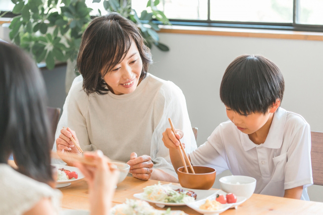 ご飯を食べる子供とそれを見守る母親の画像