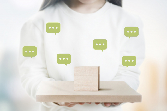 人が持っている板の上に木の立方体が置かれ空中にコメントマークが浮いている画像