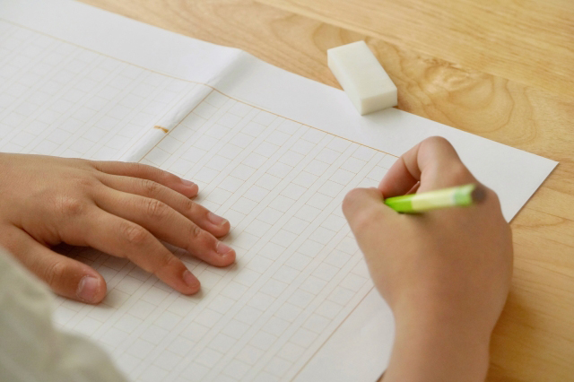 作文用紙に文字を書こうとしている子供の画像