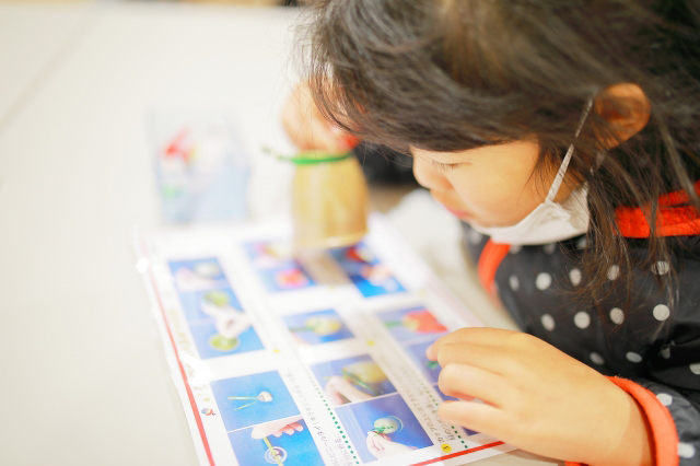 実験の順序が書かれた本を読む子供の画像