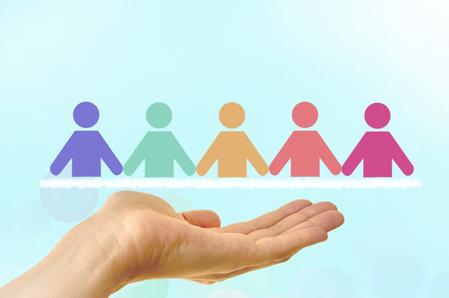 手の上にいろいろな色の人型のイラストが乗っている画像