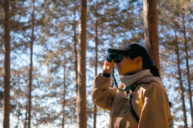 山の中で、子どもが望遠鏡を使って何かを観察している様子の画像